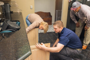 TriForce Restoration technician inspecting water damage under kitchen cabinets to prevent mold growth after a water loss