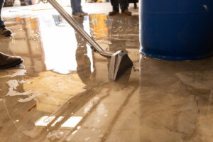 Water mitigation technician extracting standing water from a concrete floor during a water damage restoration job