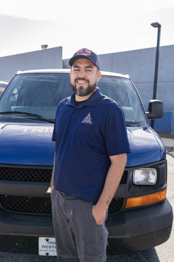 Field team member of a restoration contractor standing in front of a service truck for a water mitigation company specializing in water removal.