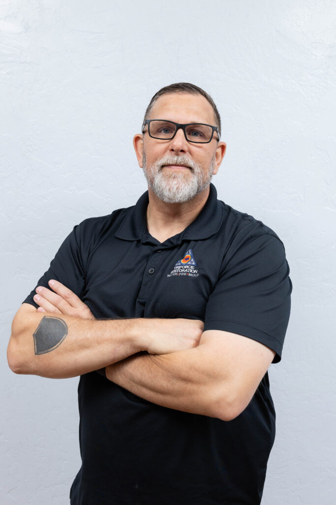 Experienced restoration contractor team member with arms crossed, representing water removal expertise at a trusted water mitigation company.