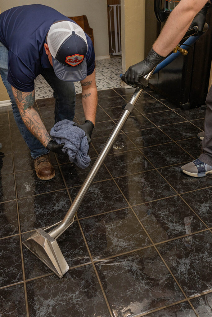 Technicians performing professional water mitigation using extraction equipment for water damage restoration and water removal services inside a residential property.