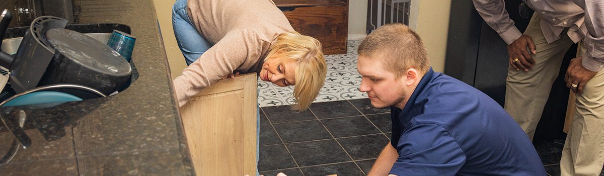 TriForce Restoration technician inspecting water damage under kitchen cabinets to prevent mold growth after a water loss